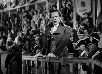 Movie still from “A Tale of Two Cities” (1935), directed by Jack Conway – A black and white photo of a man standing in front of an audience; Medium shot, High angle