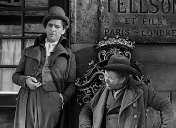 Movie still from “A Tale of Two Cities” (1935), directed by Jack Conway – Two men are sitting on a chair in a black and white photo; Medium shot, Over the shoulder angle