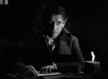 Movie still from “A Tale of Two Cities” (1935), directed by Jack Conway – A black and white photo of a man writing at a table; Medium shot, Low angle