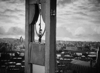 Movie still from “A Tale of Two Cities” (1935), directed by Jack Conway – A guillotine with a view of a city in the background; Extreme Wide shot, Low angle