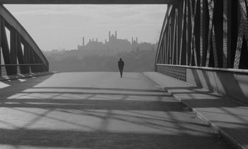 A person walking across a bridge with a city in the background