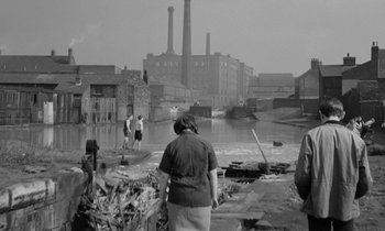 An older woman standing in front of an old factory