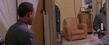 Movie still from “A Thin Line Between Love and Hate” (1996), directed by Martin Lawrence – A man standing in front of a mirror in a living room; Medium shot, Over the shoulder angle