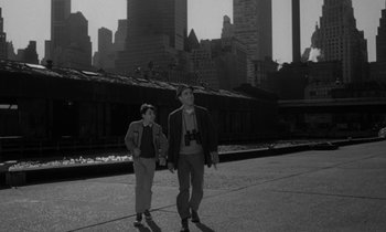 Movie still from “A Thousand Clowns” (1965), directed by Fred Coe – A man and a woman holding hands while walking down a street; Wide shot, High angle