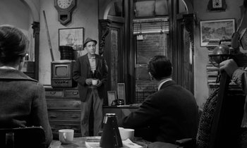 Movie still from “A Thousand Clowns” (1965), directed by Fred Coe – A man standing in front of another man in front of a television; Medium shot, Over the shoulder angle
