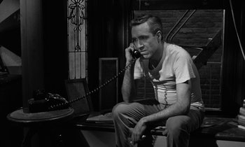 Movie still from “A Thousand Clowns” (1965), directed by Fred Coe – A man talking on a phone while sitting on a chair; Medium shot, High angle
