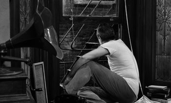 Movie still from “A Thousand Clowns” (1965), directed by Fred Coe – A man squatting on the ground in front of a window; Medium shot, Low angle