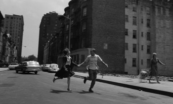 Movie still from “A Thousand Clowns” (1965), directed by Fred Coe – A man and a woman holding hands while walking down a street; Wide shot, High angle
