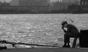 Movie still from “A Thousand Clowns” (1965), directed by Fred Coe – A man sitting on a dock looking at the water; Wide shot, High angle