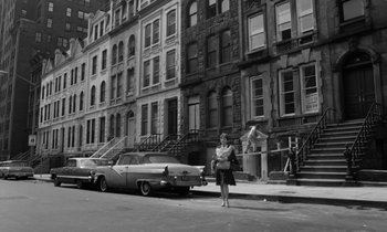 Movie still from “A Thousand Clowns” (1965), directed by Fred Coe – A woman standing on the side of the road in front of a car; Wide shot, High angle