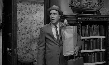 Movie still from “A Thousand Clowns” (1965), directed by Fred Coe – A black and white photo of a man in a suit holding a paper bag; Medium shot, High angle