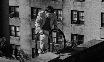 Movie still from “A Thousand Clowns” (1965), directed by Fred Coe – A man standing on top of a building near a window; Wide shot, High angle