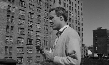 Movie still from “A Thousand Clowns” (1965), directed by Fred Coe – A black and white photo of a man in front of a building; Medium shot, Low angle