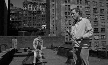 Movie still from “A Thousand Clowns” (1965), directed by Fred Coe – Two men standing on a bench in front of a building; Wide shot, Low angle