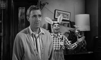 Movie still from “A Thousand Clowns” (1965), directed by Fred Coe – A man standing next to another man in a room; Medium shot, Over the shoulder angle
