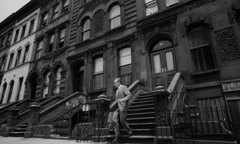 Movie still from “A Thousand Clowns” (1965), directed by Fred Coe – A black and white photo of a man walking down the steps of a building; Wide shot, Low angle