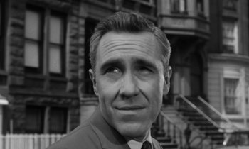 Movie still from “A Thousand Clowns” (1965), directed by Fred Coe – Black and white photograph of a man in front of a building; Close Up shot, High angle