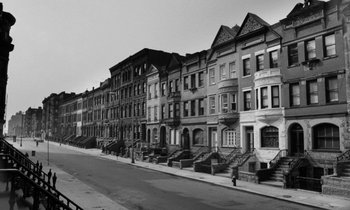 Movie still from “A Thousand Clowns” (1965), directed by Fred Coe – An old black and white photo of a row of houses; Extreme Wide shot, Low angle