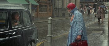 Movie still from “A Touch of Class” (1973), directed by Melvin Frank – A woman with a red hat is standing in the rain; Medium shot, Over the shoulder angle