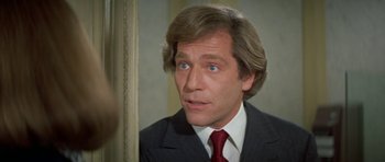 Movie still from “A Touch of Class” (1973), directed by Melvin Frank – A person wearing a suit and tie; Close Up shot, Over the shoulder angle