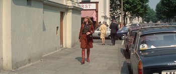 Movie still from “A Touch of Class” (1973), directed by Melvin Frank – A woman in a brown coat and red boots walking down the street; Wide shot, Low angle