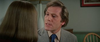 Movie still from “A Touch of Class” (1973), directed by Melvin Frank – A person wearing a suit and tie; Close Up shot, Over the shoulder angle