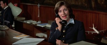 Movie still from “A Touch of Class” (1973), directed by Melvin Frank – A woman talking on a phone while sitting at a desk; Close Up shot, High angle