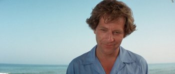 Movie still from “A Touch of Class” (1973), directed by Melvin Frank – A person wearing a blue shirt near the ocean; Close Up shot, Low angle