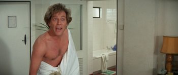 Movie still from “A Touch of Class” (1973), directed by Melvin Frank – A man in a towel in front of a bathroom mirror; Medium shot, Low angle