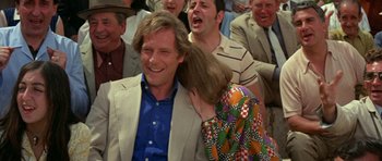 Movie still from “A Touch of Class” (1973), directed by Melvin Frank – A man and a woman hugging in front of a group of people; Medium shot, Over the shoulder angle