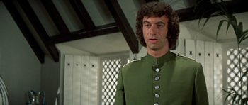 Movie still from “A Touch of Class” (1973), directed by Melvin Frank – A man in a green uniform standing in front of a wall; Close Up shot, Low angle