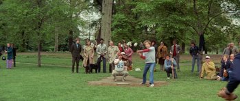 Movie still from “A Touch of Class” (1973), directed by Melvin Frank – A group of people in a park watching a baseball game; Wide shot, Over the shoulder angle