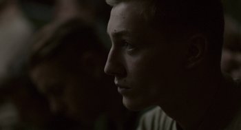 Movie still from “A War” (2015), directed by Tobias Lindholm – A young man looking into the distance in the dark; Close Up shot, Over the shoulder angle
