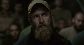 Movie still from “A War” (2015), directed by Tobias Lindholm – A man with a long beard wearing a hat; Close Up shot, Over the shoulder angle