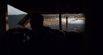 Movie still from “A War” (2015), directed by Tobias Lindholm – A man sitting in a chair in a dark room; Medium shot, Over the shoulder angle