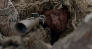 Movie still from “A War” (2015), directed by Tobias Lindholm – A man with a rifle in a camouflage suit; Close Up shot, Over the shoulder angle