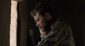 Movie still from “A War” (2015), directed by Tobias Lindholm – A man with a beard is wearing a military uniform; Close Up shot, Over the shoulder angle