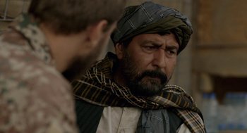 Movie still from “A War” (2015), directed by Tobias Lindholm – A man with a beard wearing a hat and a scarf; Close Up shot, Over the shoulder angle
