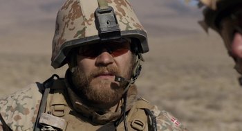 Movie still from “A War” (2015), directed by Tobias Lindholm – A person wearing a helmet; Close Up shot, Over the shoulder angle