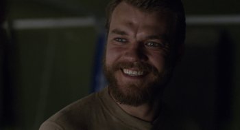 Movie still from “A War” (2015), directed by Tobias Lindholm – A person with a beard smiling; Close Up shot, Over the shoulder angle