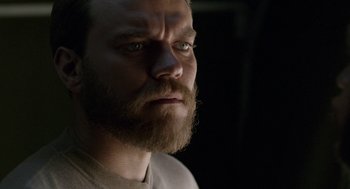 Movie still from “A War” (2015), directed by Tobias Lindholm – A person with a beard looking at the camera; Close Up shot, Over the shoulder angle