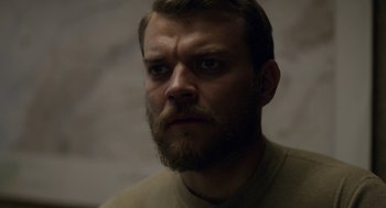 Movie still from “A War” (2015), directed by Tobias Lindholm – A person with a beard looking at the camera; Close Up shot, Over the shoulder angle