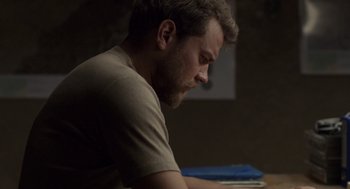 Movie still from “A War” (2015), directed by Tobias Lindholm – A person sitting at a table with a laptop; Close Up shot, Over the shoulder angle