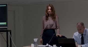 Movie still from “A War” (2015), directed by Tobias Lindholm – A woman standing in front of a table with a laptop; Medium shot, Over the shoulder angle