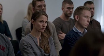 Movie still from “A War” (2015), directed by Tobias Lindholm – A group of people sitting in front of a white wall; Medium shot, Over the shoulder angle