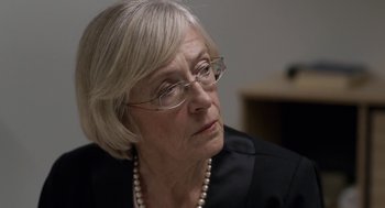 Movie still from “A War” (2015), directed by Tobias Lindholm – An older woman wearing glasses and a black jacket; Close Up shot, Over the shoulder angle