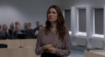 Movie still from “A War” (2015), directed by Tobias Lindholm – A woman standing in front of a group of people; Medium shot, Over the shoulder angle
