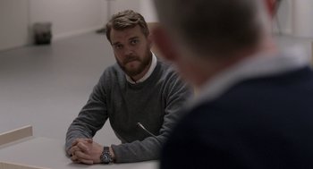 Movie still from “A War” (2015), directed by Tobias Lindholm – A man sitting in front of another man in front of a white wall; Medium shot, Over the shoulder angle