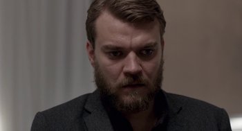 Movie still from “A War” (2015), directed by Tobias Lindholm – A person wearing a suit and beard; Close Up shot, Over the shoulder angle