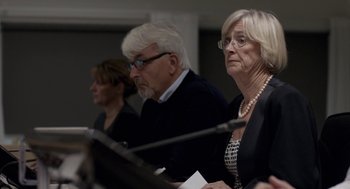 Movie still from “A War” (2015), directed by Tobias Lindholm – A group of people sitting next to each other in front of microphones; Close Up shot, Over the shoulder angle